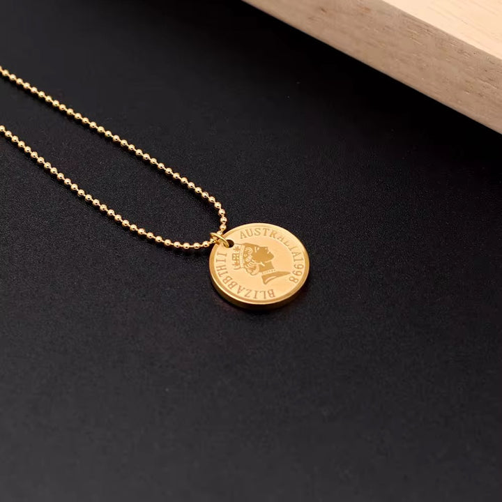 Gold necklace with a round pendant on a dark surface