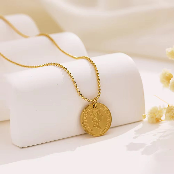 Gold necklace with a round pendant on a white surface