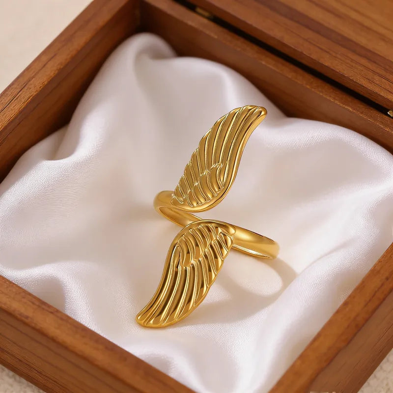 Gold wing-shaped ring in a wooden box with white fabric lining