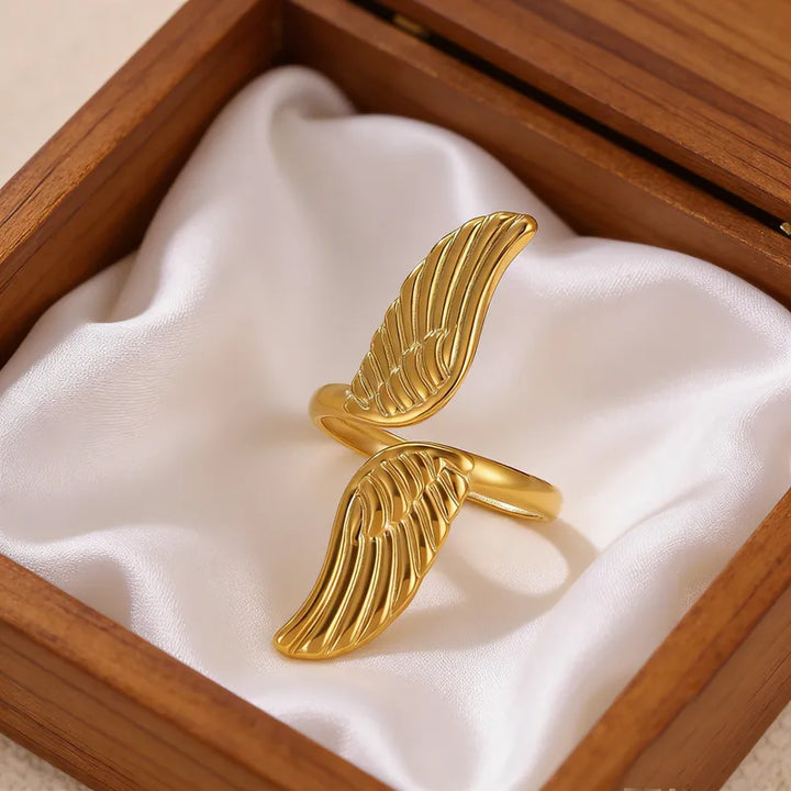 Gold wing-shaped ring in a wooden box with white fabric lining