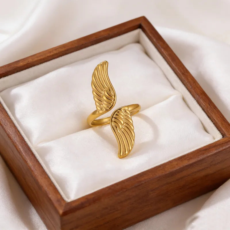 Gold wing-shaped ring in a wooden box with white interior