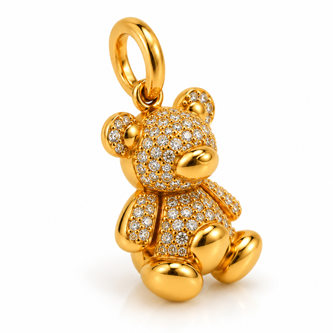 A gold teddy bear pendant fully paved with small clear stones, shown on a clean white background.