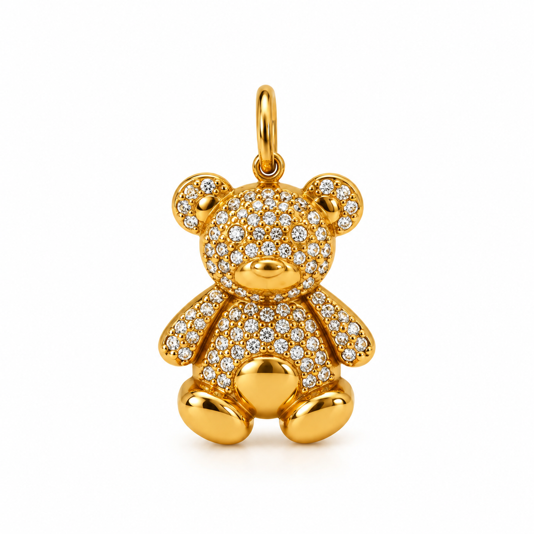 A gold teddy bear pendant encrusted with small clear stones, shown on a clean white background.