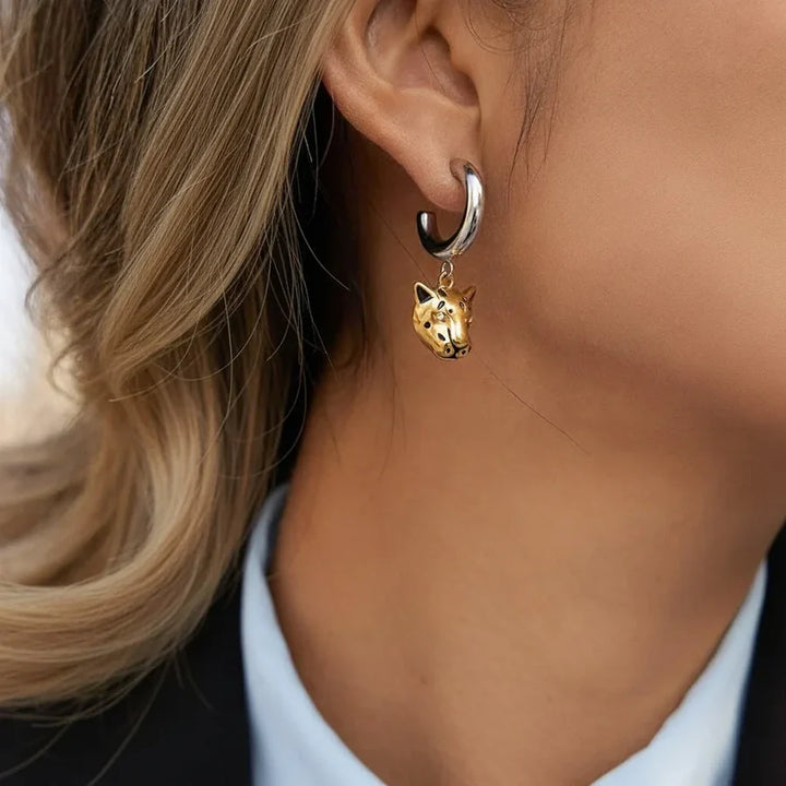 Gold dog-shaped earring worn by a person with blonde hair.