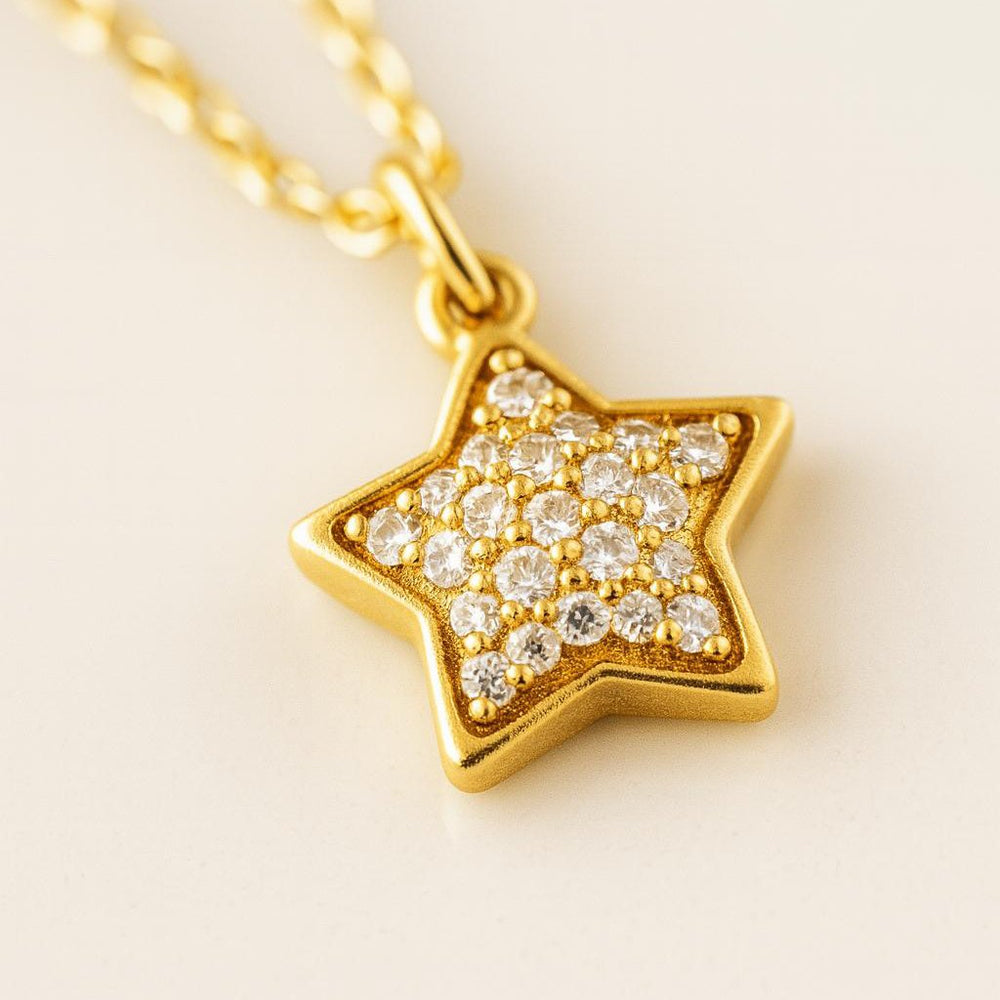 Gold star-shaped pendant with embedded diamonds on a light background