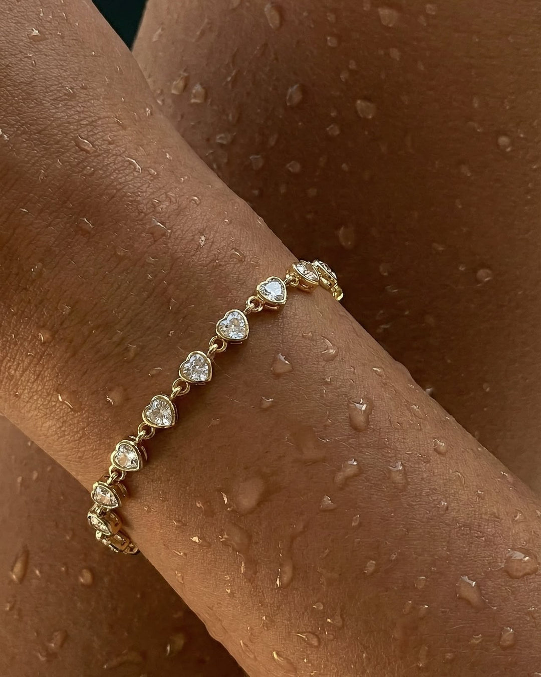 Gold bracelet with heart-shaped gemstones on a person&