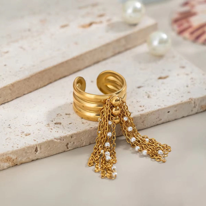 Gold ring with pearl tassels on a stone surface