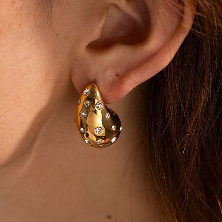Gold earring with gemstones worn by a person
