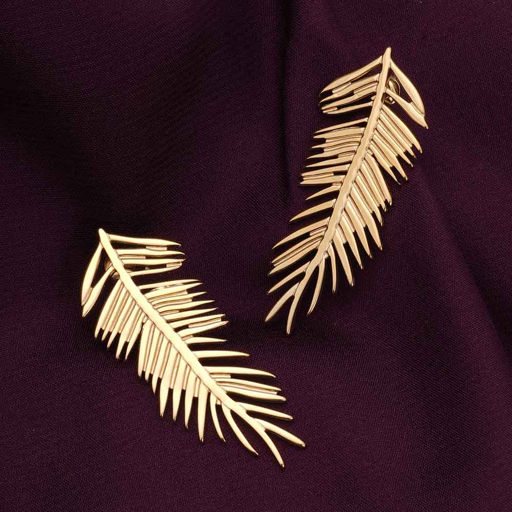 Gold leaf earrings on a dark purple fabric background