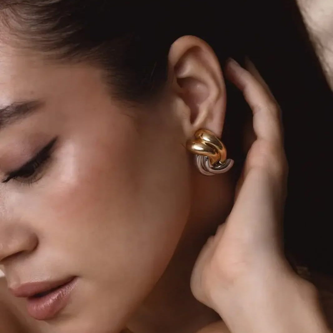 Close-up of a woman wearing gold hoop earrings with a soft focus background
