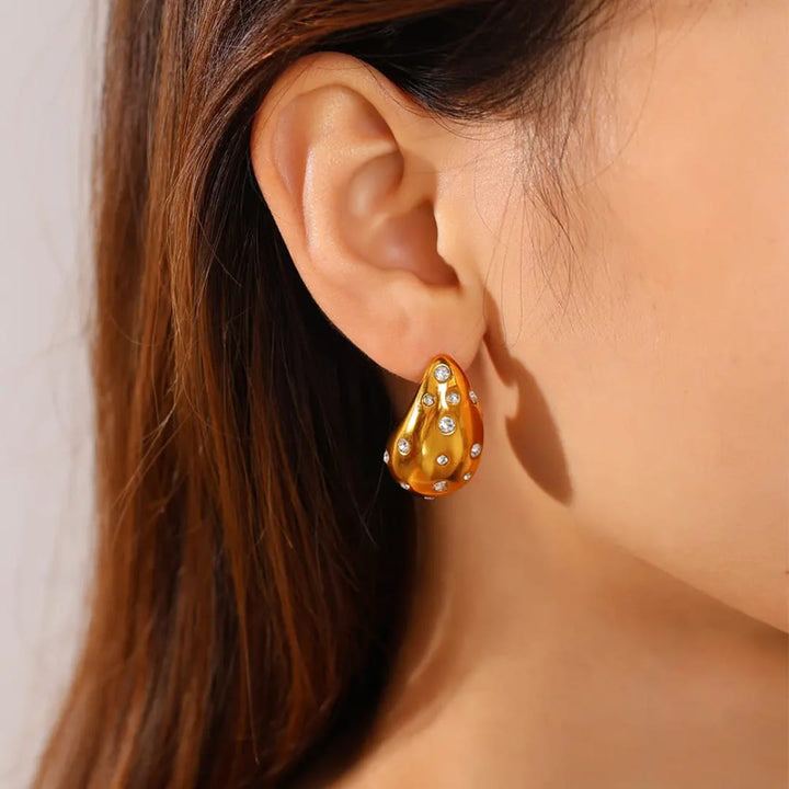 Gold earring with gemstones worn by a person