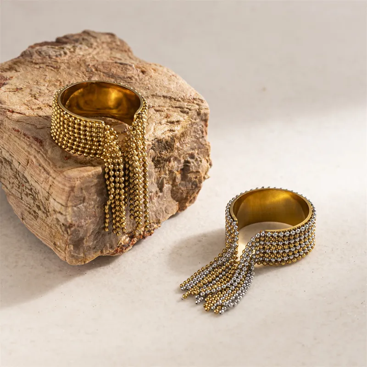 Gold and silver beaded bracelets on a textured surface with a rock background