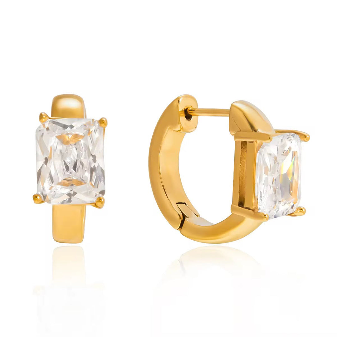 A pair of gold huggie hoop earrings with rectangular clear gemstones, shown from front and side angles on a white background.