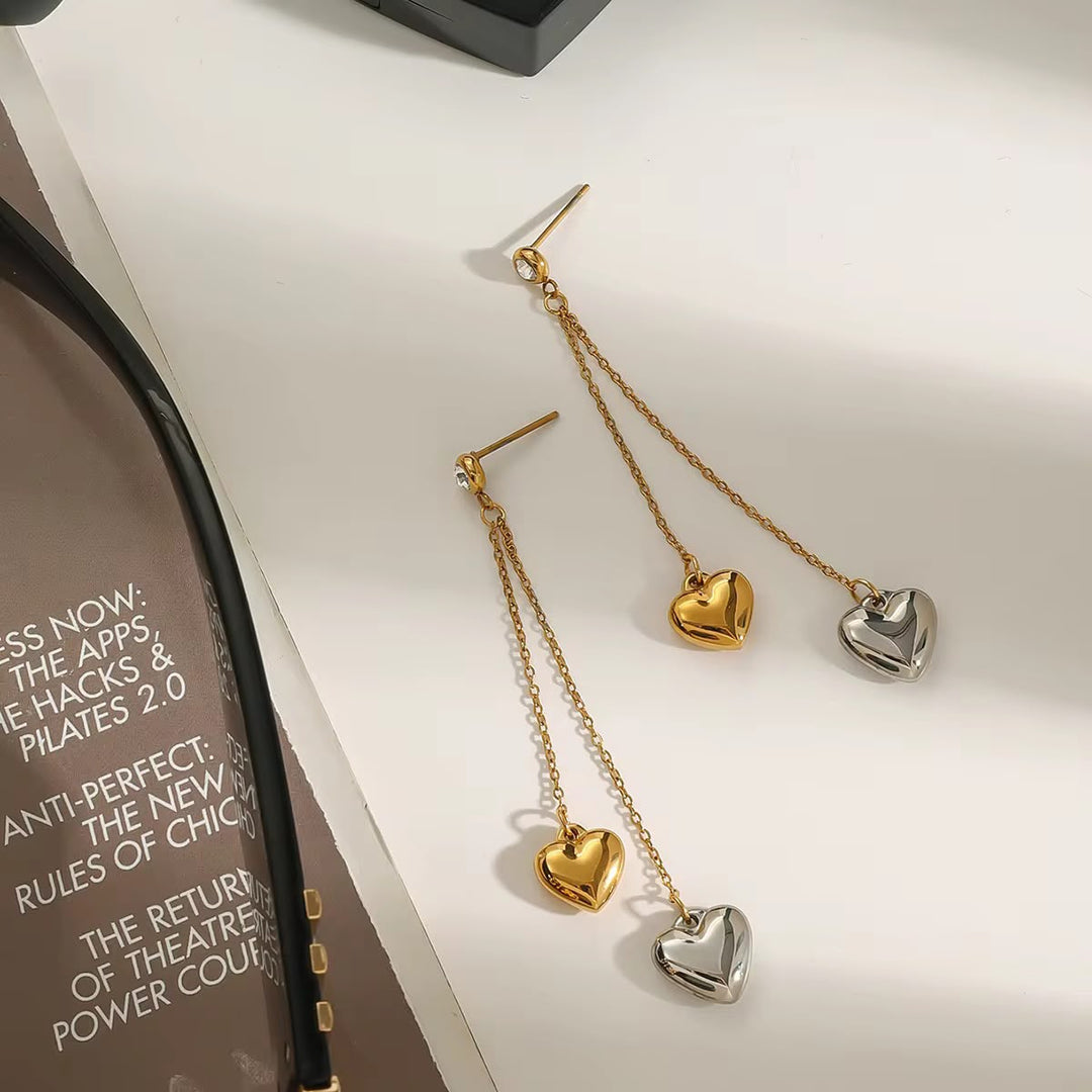Heart-shaped earrings on a white surface with a book in the background